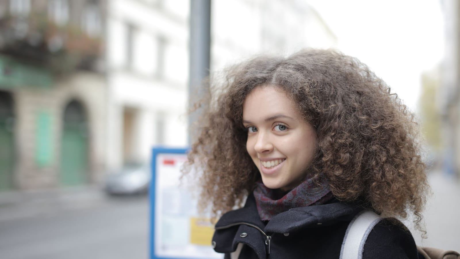 Smiling woman with voluminous, springy curls on a city street