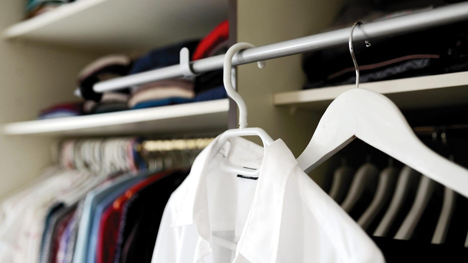 White shirt on a hanger in a closet filled with hanging clothes and shelves
