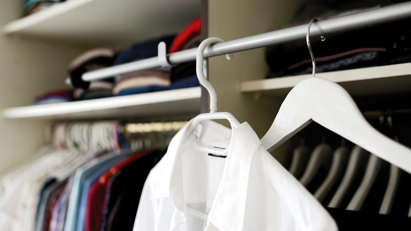 White shirt on a hanger in a closet filled with hanging clothes and shelves