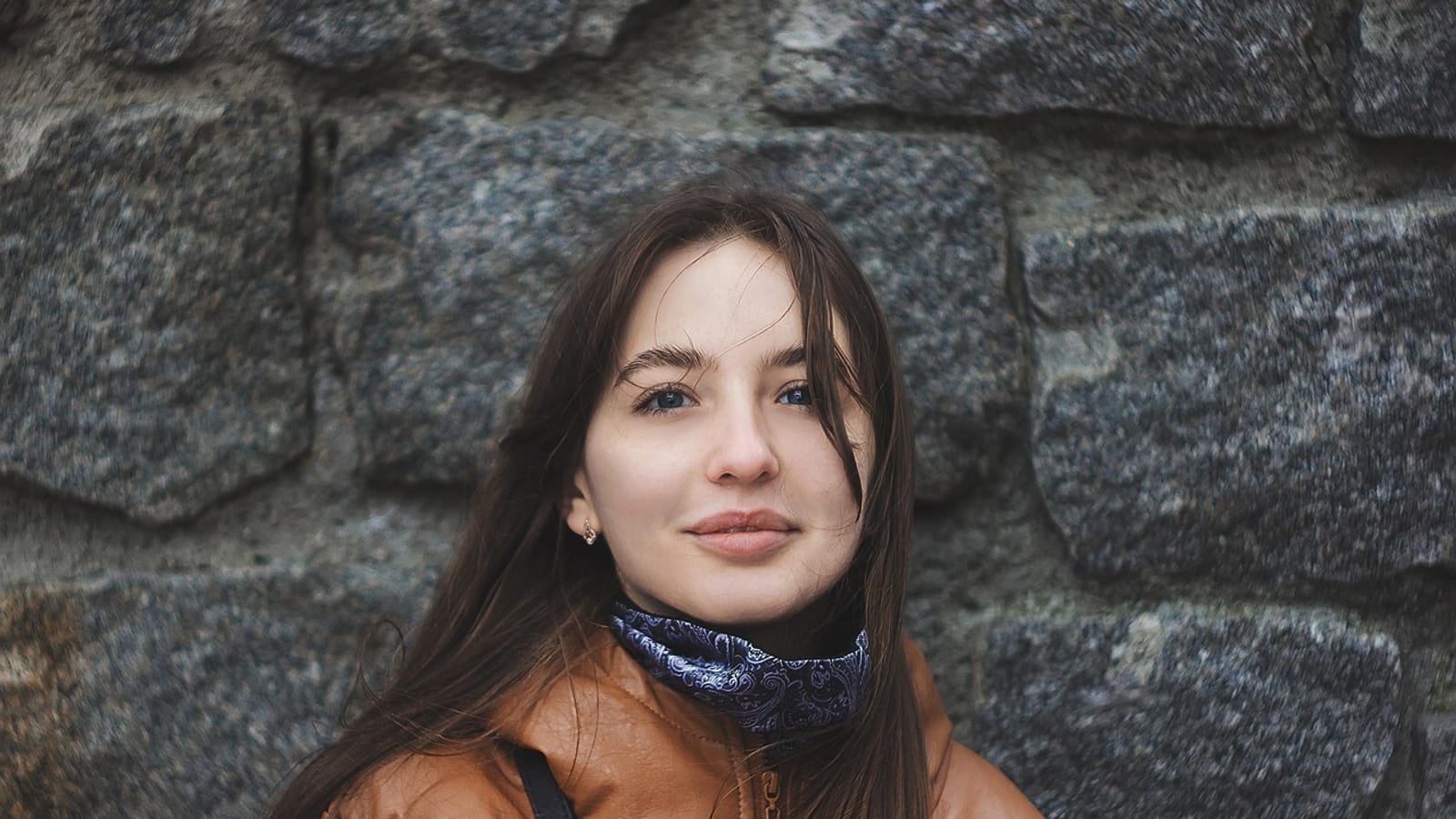 Woman in a winter coat and scarf with brown hair, soft daylight