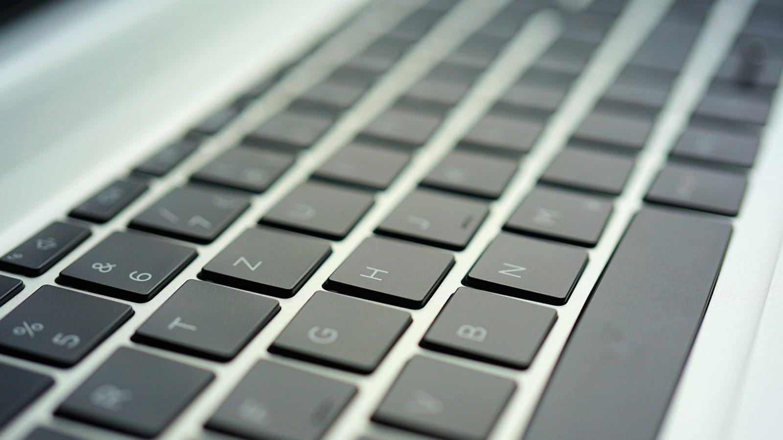 Close-up of a silver laptop keyboard photographed at an angle in soft light