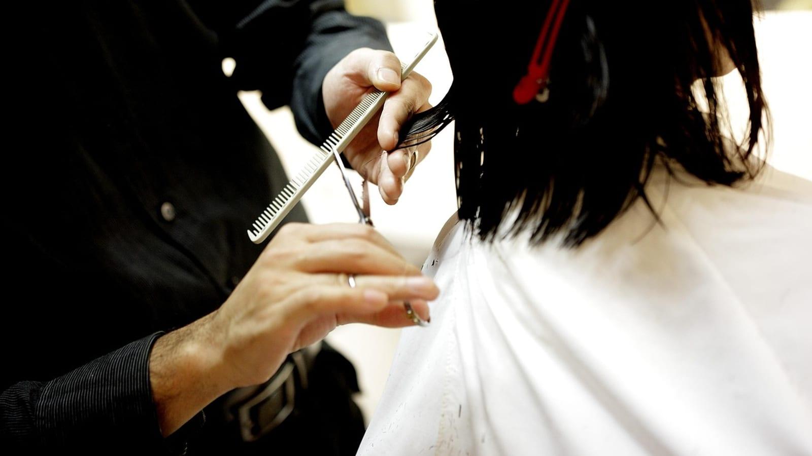 Hairdresser cutting hair with a comb and scissors in a salon