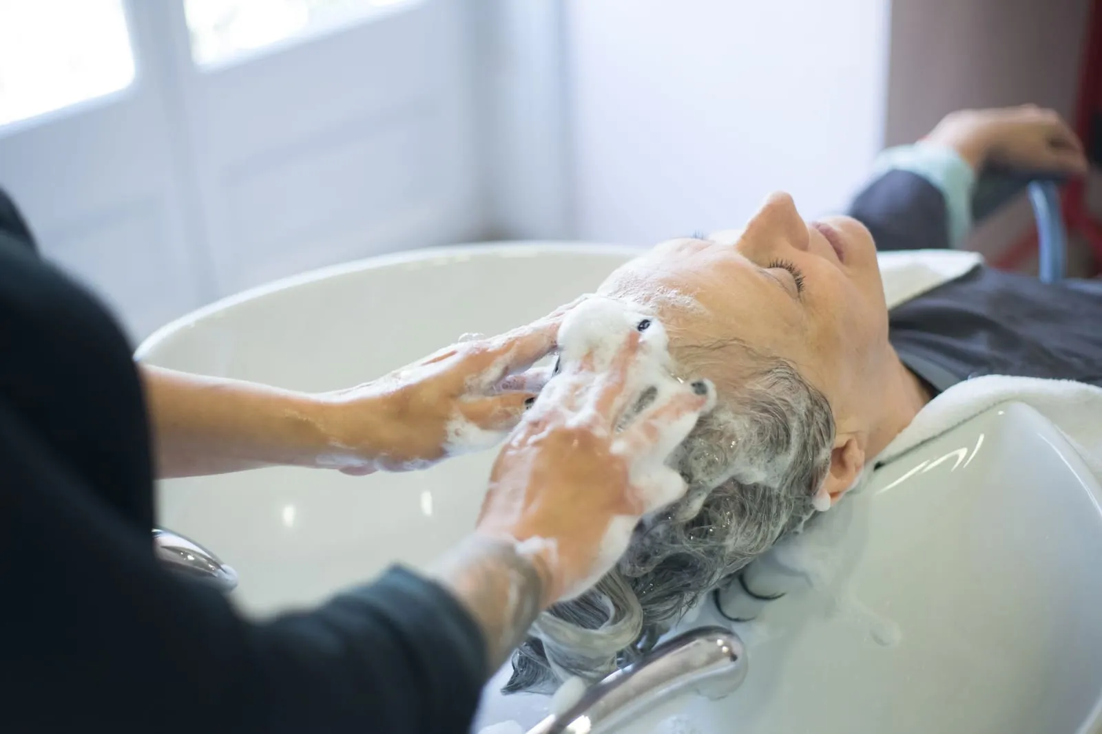 Hair being rinsed at a sink with gentle fingertip pressure