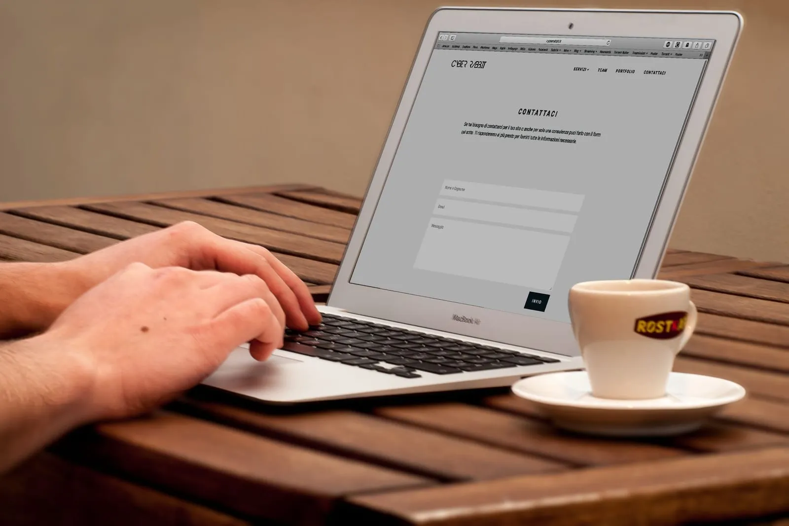 Hands typing on a laptop next to a cup of coffee