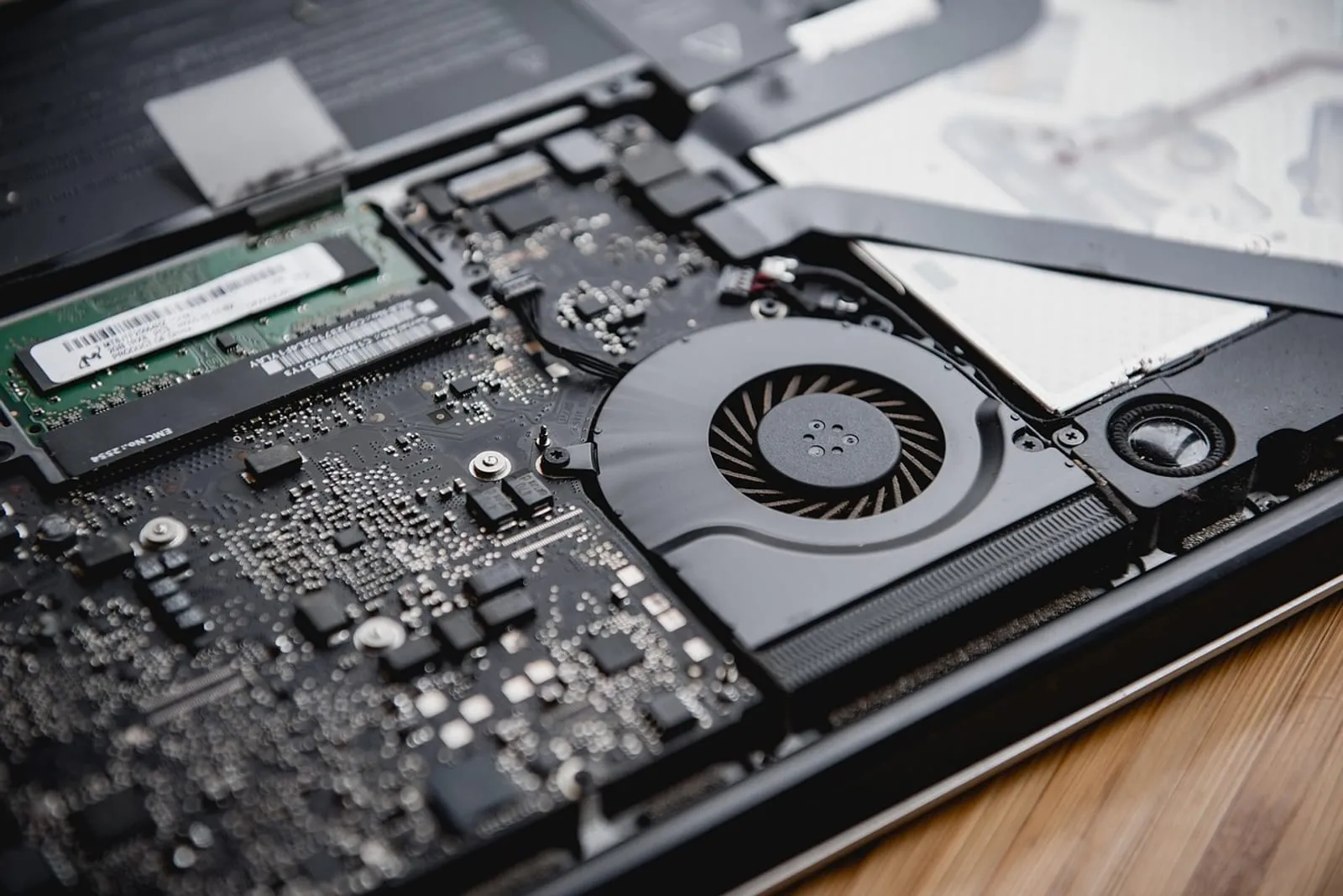 Inside of an opened laptop showing the cooling fan and memory