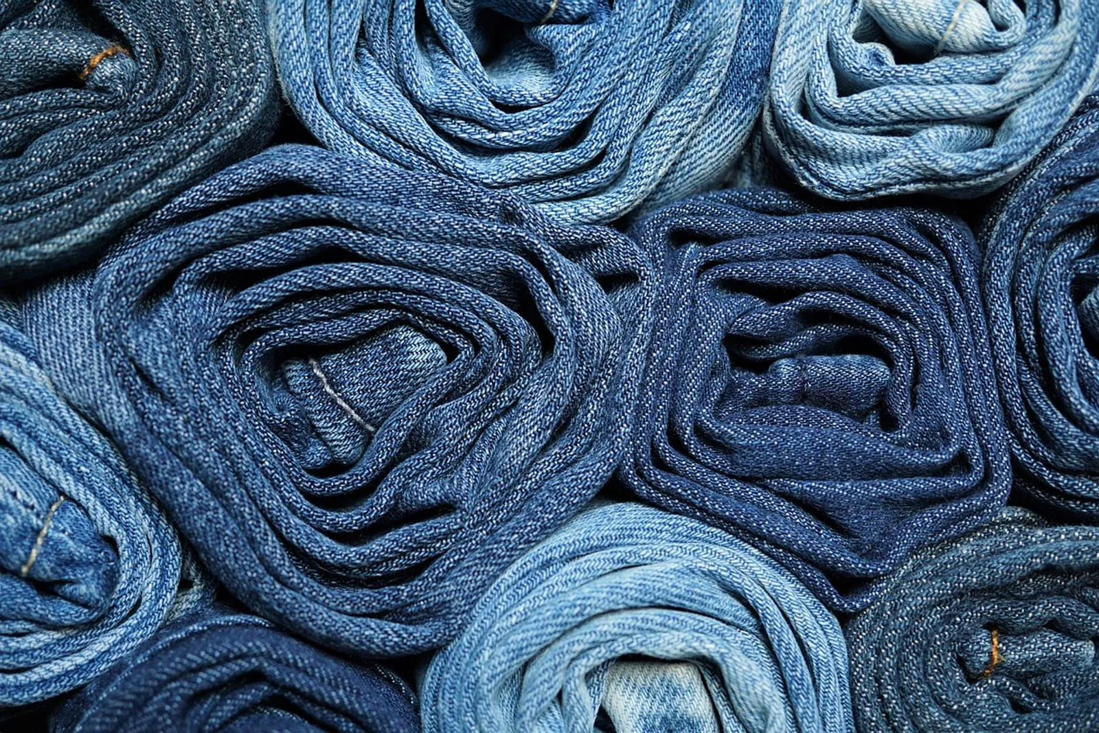 Denim jeans rolled up and stacked tightly side by side