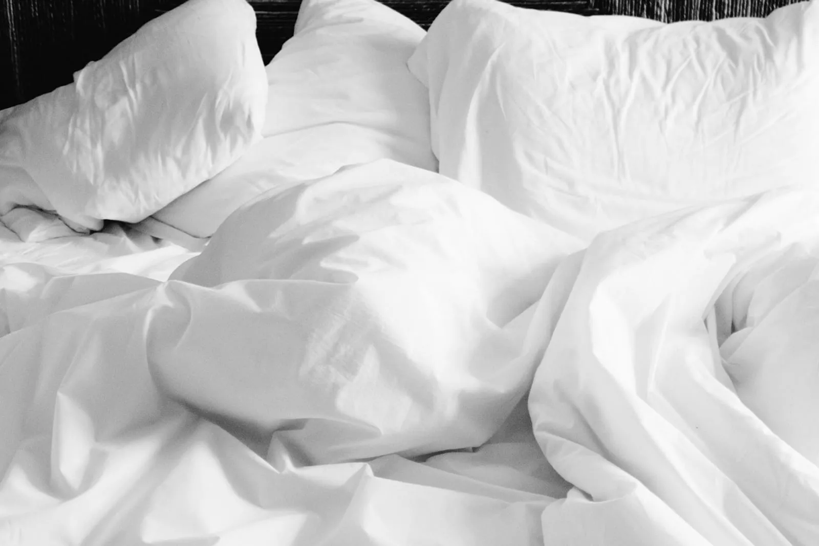 Soft white pillows and sheets on an unmade bed