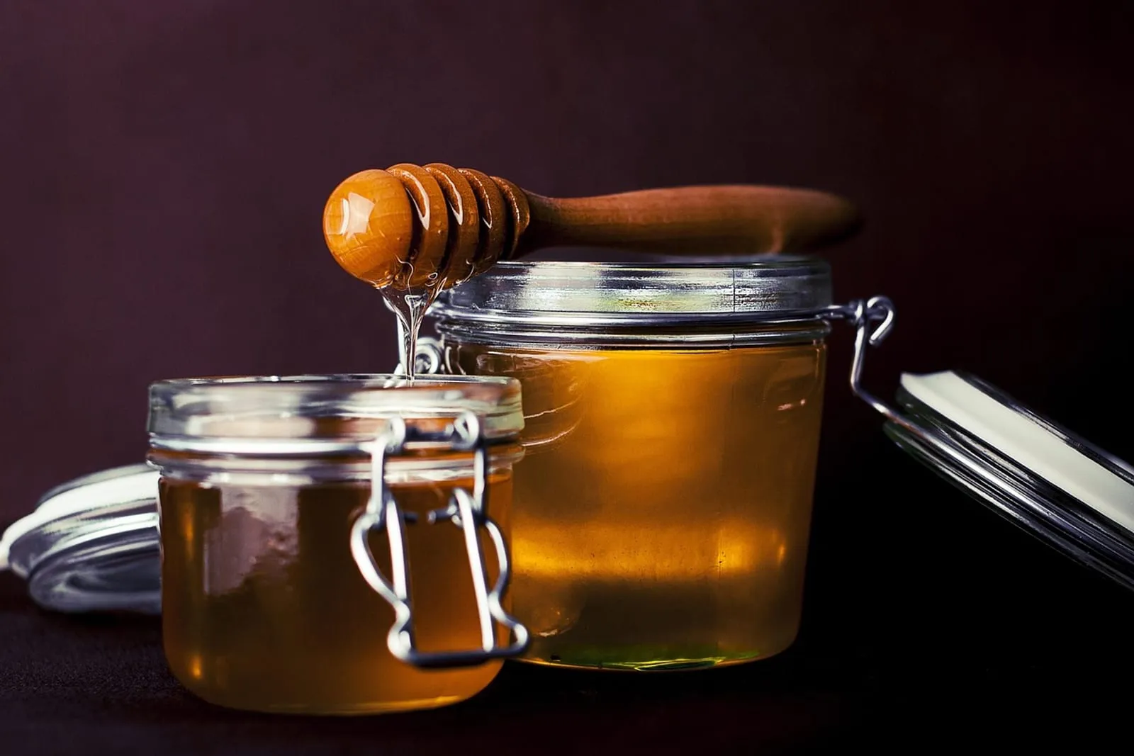 Glass jar of honey with a wooden honey dipper