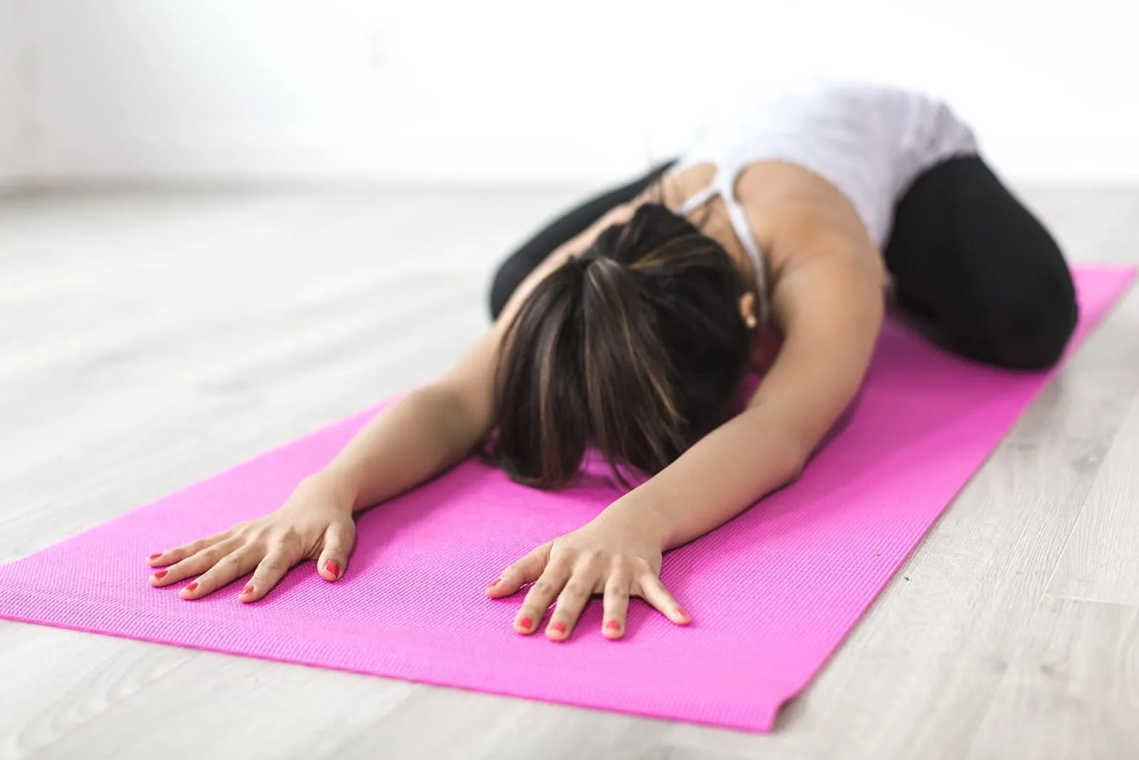 Woman stretching in child's pose on a pink yoga mat
